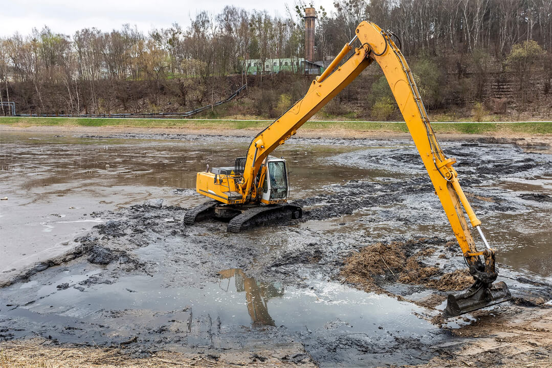 Excavator Releasing Water From Drainage Ditch